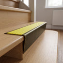 Solid brass stair nosing 71mm raked back in antique brass with yellow castellated insert fitted on an oak domestic hallway staircase