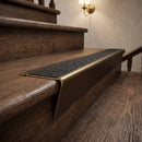Solid brass stair nosing 71mm raked back in antique bronze with black olympic grip insert fitted on a vinyl plank school staircase