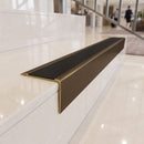 Solid brass stair nosing 71mm raked back in antique bronze with black smooth textured insert fitted on a granite atrium staircase