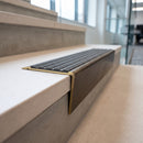 Solid brass stair nosing 71mm raked back in antique bronze with granite castellated insert fitted on a dark oak hotel stairwell