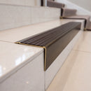 Solid brass stair nosing 71mm raked back in antique bronze with peat castellated insert fitted on a dark oak hotel stairwell