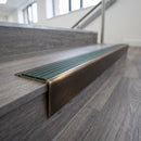 Solid brass stair nosing 71mm raked back in antique bronze with spruce castellated insert fitted on a vinyl plank school staircase