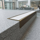 Solid brass stair nosing 71mm raked back in antique bronze with white castellated insert fitted on a granite atrium staircase