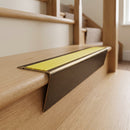 Solid brass stair nosing 71mm raked back in antique bronze with yellow castellated insert fitted on an oak domestic hallway staircase