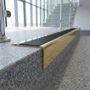 Solid brass stair nosing 71mm raked back in polished brass with black smooth textured insert fitted on a granite atrium staircase