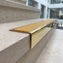 Solid brass stair nosing 71mm raked back in polished brass with gold castellated insert fitted on a limestone office staircase