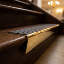 Solid brass stair nosing 71mm raked back in polished brass with granite castellated insert fitted on a dark oak hotel stairwell