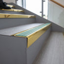 Solid brass stair nosing 71mm raked back in polished brass with jade castellated insert fitted on a vinyl plank school staircase