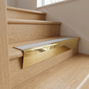 Solid brass stair nosing 71mm raked back in polished brass with light grey smooth textured insert fitted on an oak domestic hallway staircase