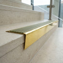 Solid brass stair nosing 71mm raked back in polished brass with olive castellated insert fitted on a limestone office staircase