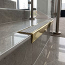 Solid brass stair nosing 71mm raked back in polished brass with polar grey castellated insert fitted on a porcelain tiled hotel lobby staircase