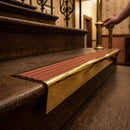 Solid brass stair nosing 71mm raked back in polished brass with rustic castellated insert fitted on a dark oak hotel stairwell