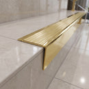 Solid brass stair nosing 71mm raked back in polished brass with satin brass insert fitted on a porcelain tiled hotel lobby staircase