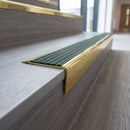 Solid brass stair nosing 71mm raked back in polished brass with spruce castellated insert fitted on a vinyl plank school staircase