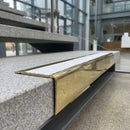 Solid brass stair nosing 71mm raked back in polished brass with white castellated insert fitted on a granite atrium staircase