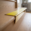 Solid brass stair nosing 71mm raked back in polished brass with yellow castellated insert fitted on an oak domestic hallway staircase