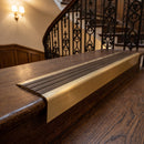 Solid brass stair nosing 71mm raked back in satin brass with antique bronze insert fitted on a dark oak hotel stairwell