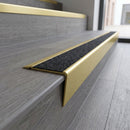 Solid brass stair nosing 71mm raked back in satin brass with black olympic grip insert fitted on a vinyl plank school staircase