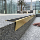 Solid brass stair nosing 71mm raked back in satin brass with black smooth textured insert fitted on a granite atrium staircase