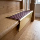 Solid brass stair nosing 71mm raked back in satin brass with claret castellated insert fitted on an oak domestic hallway staircase
