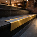Solid brass stair nosing 71mm raked back in satin brass with flint castellated insert fitted on a slate restaurant staircase