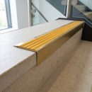 Solid brass stair nosing 71mm raked back in satin brass with gold castellated insert fitted on a limestone office staircase