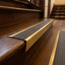 Solid brass stair nosing 71mm raked back in satin brass with granite castellated insert fitted on a dark oak hotel stairwell