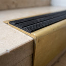 Close-up of the black castellated anti-slip insert and raked-back nose on a satin brass 71mm stair nosing