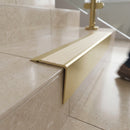 Solid brass stair nosing 71mm raked back in satin brass with ivory castellated insert fitted on a porcelain tiled hotel lobby staircase
