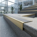 Solid brass stair nosing 71mm raked back in satin brass with light grey castellated insert fitted on a granite atrium staircase