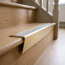 Solid brass stair nosing 71mm raked back in satin brass with light grey smooth textured insert fitted on an oak domestic hallway staircase