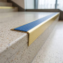 Solid brass stair nosing 71mm raked back in satin brass with mid blue castellated insert fitted on a terrazzo museum foyer staircase