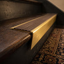 Solid brass stair nosing 71mm raked back in satin brass with peat castellated insert fitted on a dark oak hotel stairwell