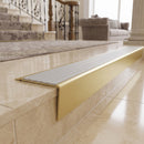 Solid brass stair nosing 71mm raked back in satin brass with polar grey castellated insert fitted on a porcelain tiled hotel lobby staircase