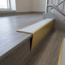 Solid brass stair nosing 71mm raked back in satin brass with polar grey smooth textured insert fitted on a vinyl plank school staircase