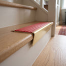 Solid brass stair nosing 71mm raked back in satin brass with poppy castellated insert fitted on an oak domestic hallway staircase