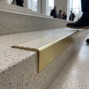 Solid brass stair nosing 71mm raked back in satin brass with porth stone castellated insert fitted on a terrazzo museum foyer staircase