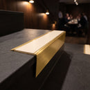 Solid brass stair nosing 71mm raked back in satin brass with porth stone smooth textured insert fitted on a slate restaurant staircase