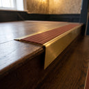 Solid brass stair nosing 71mm raked back in satin brass with rustic castellated insert fitted on a dark oak hotel stairwell