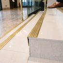 Solid brass stair nosing 71mm raked back in satin brass with satin brass insert fitted on a porcelain tiled hotel lobby staircase