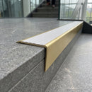 Solid brass stair nosing 71mm raked back in satin brass with white castellated insert fitted on a granite atrium staircase
