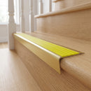 Solid brass stair nosing 71mm raked back in satin brass with yellow castellated insert fitted on an oak domestic hallway staircase