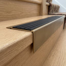 Solid Brass Stair Nosing 71mm Tread Square Front Slimline in Antique Brass finish with Black Castellated insert fitted on a residential oak staircase