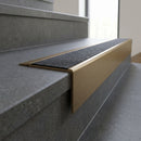 Solid Brass Stair Nosing 71mm Tread Square Front Slimline in Antique Brass finish with Black Olympic Grip insert fitted on a public building staircase with dark stone treads