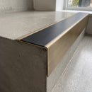 Solid Brass Stair Nosing 71mm Tread Square Front Slimline in Antique Brass finish with Black Smooth Textured insert fitted on a retail store staircase with polished concrete treads