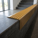 Solid Brass Stair Nosing 71mm Tread Square Front Slimline in Antique Brass finish with Gold Castellated insert fitted on a public building staircase with dark stone treads