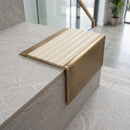 Solid Brass Stair Nosing 71mm Tread Square Front Slimline in Antique Brass finish with Ivory Castellated insert fitted on a modern office reception staircase with porcelain tile treads