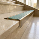 Solid Brass Stair Nosing 71mm Tread Square Front Slimline in Antique Brass finish with Jade Castellated insert fitted on a hotel lobby staircase with cream marble treads