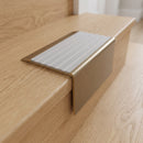 Solid Brass Stair Nosing 71mm Tread Square Front Slimline in Antique Brass finish with Light Grey Castellated insert fitted on a residential oak staircase