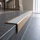 Solid Brass Stair Nosing 71mm Tread Square Front Slimline in Antique Brass finish with Light Grey Smooth Textured insert fitted on a public building staircase with dark stone treads